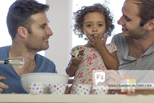 Gay couple with daughter making a cake