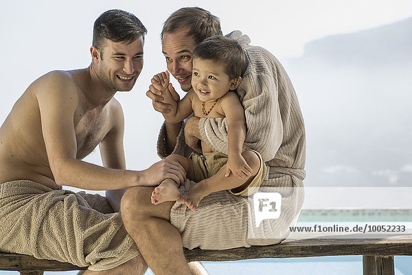 Gay couple with baby at the poolside