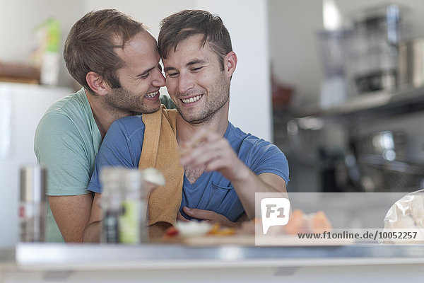 Fröhliches schwules Paar beim Zubereiten von Fleischspieße in der Küche