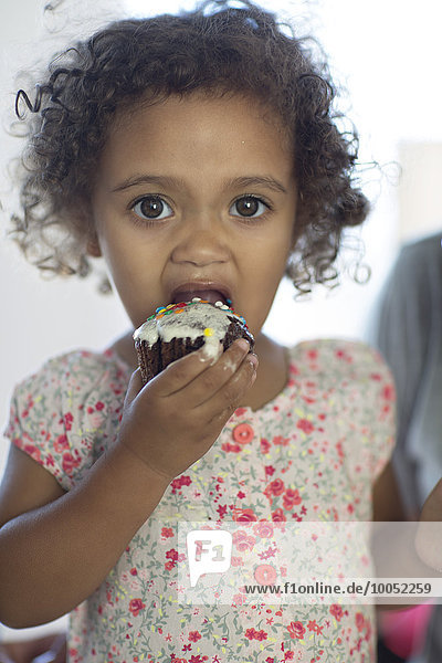 Mixed race girl eating cup cake