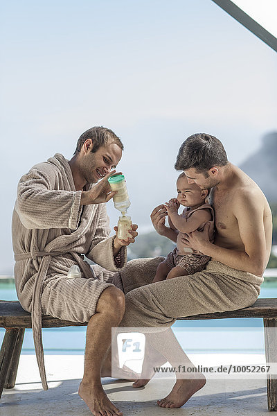 Schwules Paar macht eine Flasche für das Baby am Pool