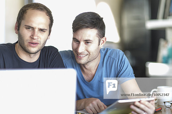 Zwei Männer mit Laptop und digitalem Tablett