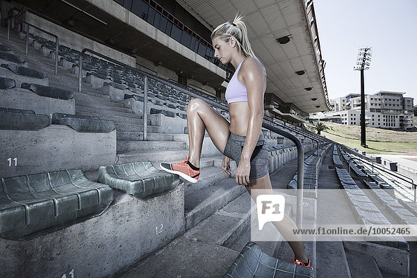 Sportlerin beim Stretching auf der Tribüne eines Stadions