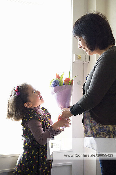 Junges Mädchen schenkt Mutter Blumen