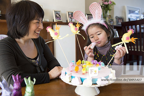 Mutter und Tochter am Tisch sitzend  Osterkuchen vor ihnen
