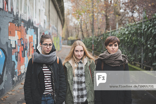 Drei Schwestern gehen durch Graffiti-Wand