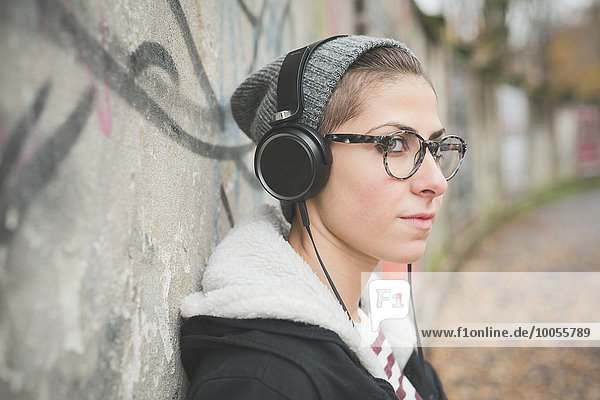 Teenager with headphones by graffiti wall