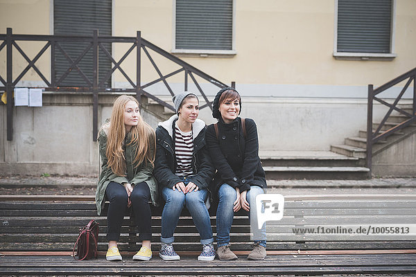 Three sisters sitting on park bench