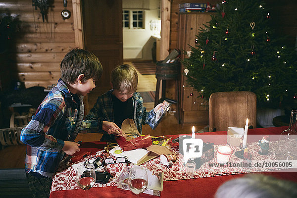 Two brothers opening Christmas presents at table