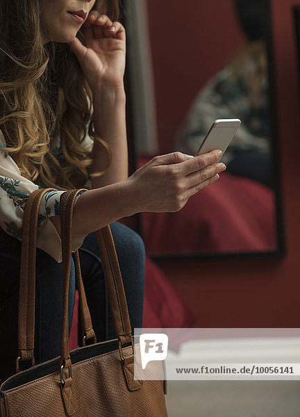 Frau betrachtet Smartphone beschnitten