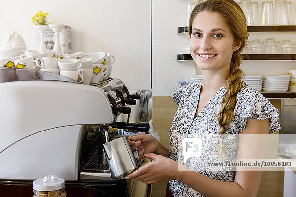 Young woman using coffee maker looking at camera  portrait