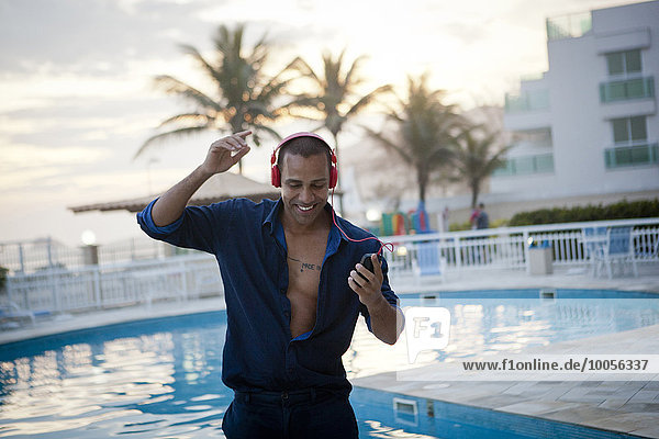 Mittlerer Erwachsener Mann tanzt zu Smartphone-Musik am Pool des Hotels  Rio De Janeiro  Brasilien