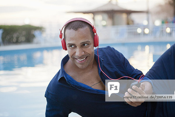 Mittlerer Erwachsener Mann  der Smartphone-Musik am Pool des Hotels hört  Rio De Janeiro  Brasilien
