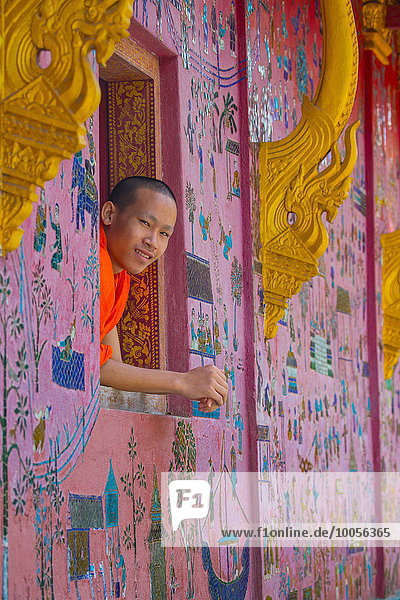 Buddhist monk looking out of Wat Xieng Thong window  Luang Prabang  Laos