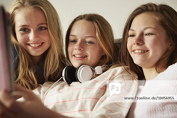 Drei Mädchen auf dem Sofa mit digitalem Tablett