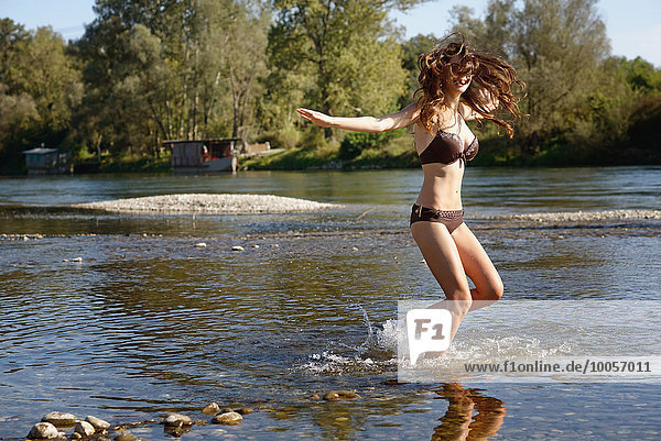 Junge Frau im Bikini beim Planschen und Spielen im Fluss
