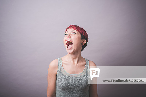 Studio-Porträt einer jungen Frau mit kurzen rosa Haaren  die schreit