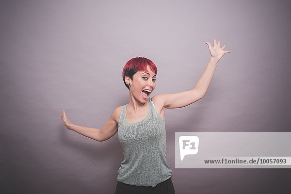 Studio-Porträt einer jungen Frau mit kurzen rosa Haaren beim Tanzen