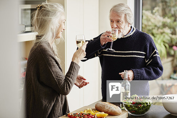 Seniorenpaar trinkt Wein in der Küche