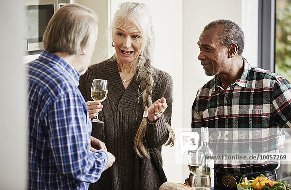 Seniorenfreunde im Gespräch in der Küche mit Wein