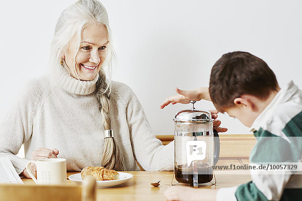 Großmutter und Enkel beim Kaffee kochen im Cafetiere
