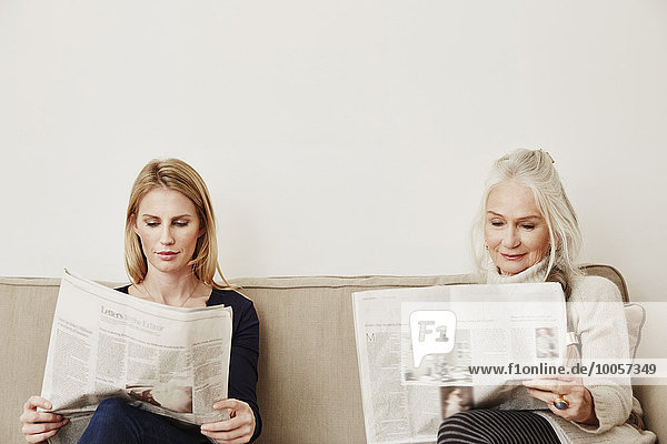 Ältere und mittlere erwachsene Frauen beim Zeitungslesen