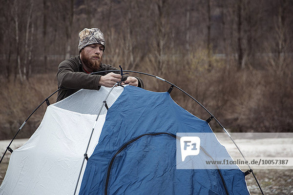 Mittlerer Erwachsener Mann beim Aufbau des Zeltes
