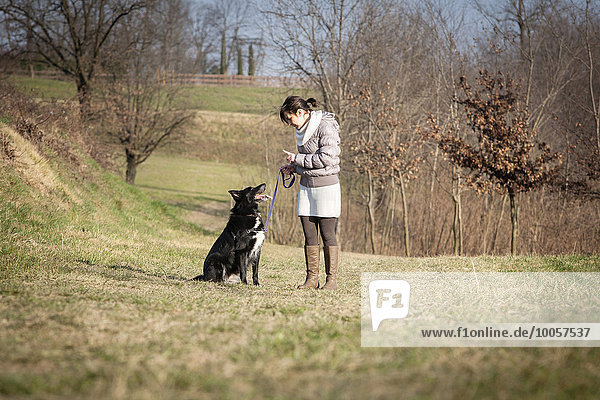 Mittlere erwachsene Frau  die mit ihrem Hund auf dem Feld spazieren geht.