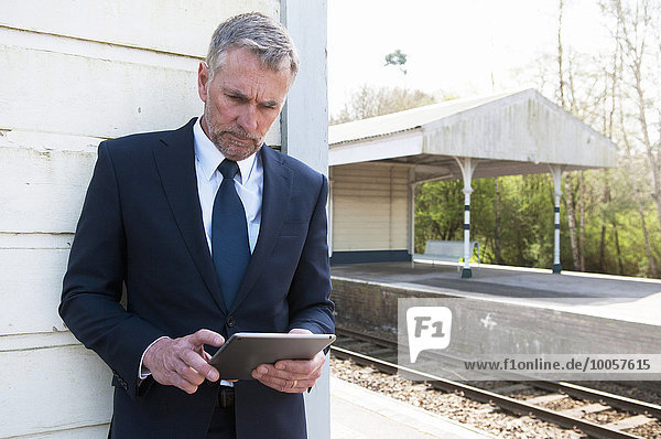 Businessman using digital tablet on railway platform
