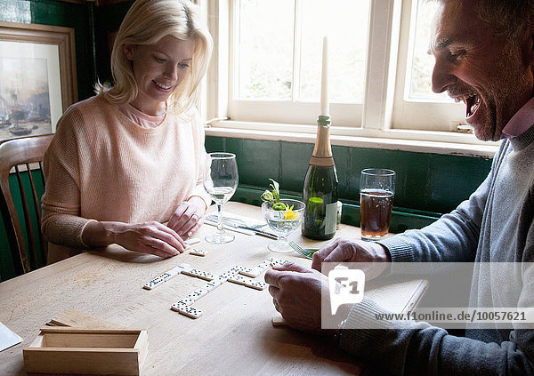 Couple drinking and playing dominoes in pub