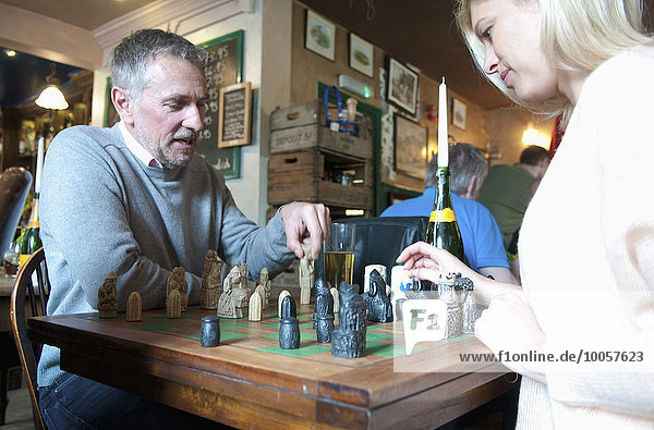 Couple playing chess in pub