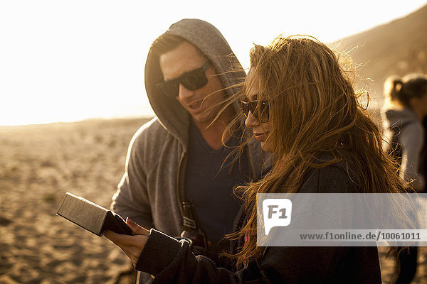 Paar mit digitalem Tablett am Strand