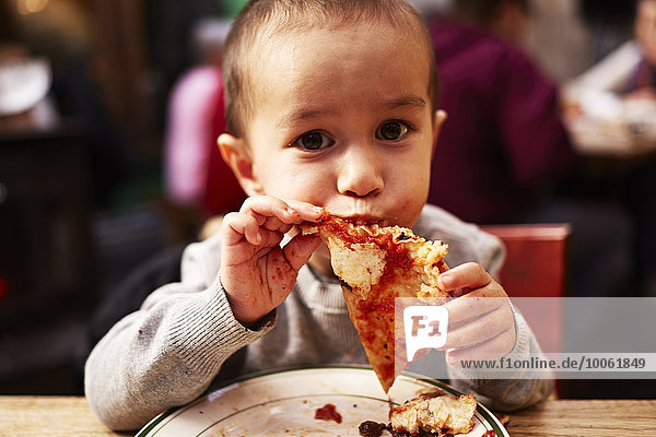 Junge isst Pizza im Restaurant