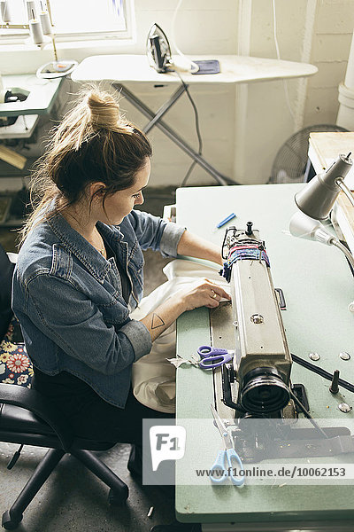 Female seamstress using sewing machine in fashion studio