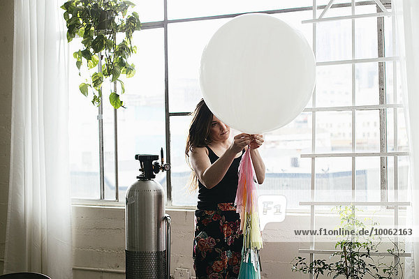 Junge Frau  die im Designstudio eine Fahne am Ballon befestigt hat