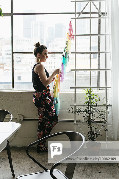 Junge Designerin  die im Designstudio eine mehrfarbige Fahne herstellt