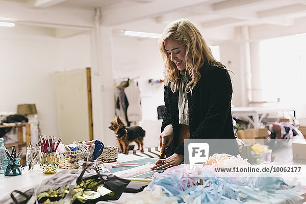 Female textile designer cutting textiles in design studio