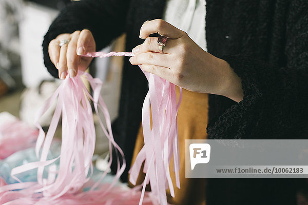 Close up of female textile designer twirling ribbons together in design studio