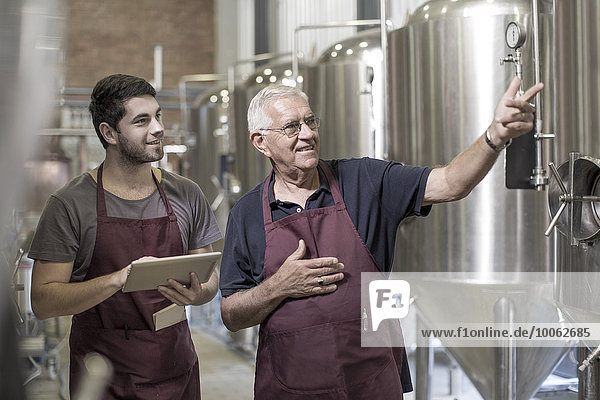 Brewers in brewery standing next to stainless steel tanks