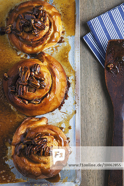 Overhead view of three sticky buns on baking tray