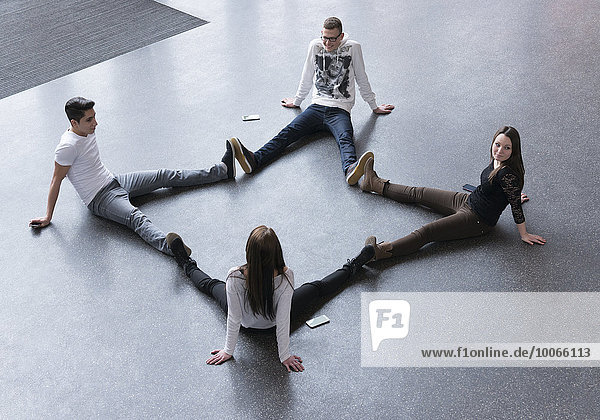 Vier Jugendliche sitzen auf dem Boden und bilden einen Stern