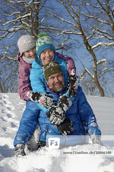 Father and his children rollicking in the snow  Bad Heilbrunn  Upper Bavaria  Bavaria  Germany  Europe