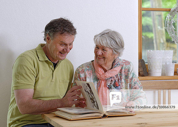 Grown-up son and elderly mother looking at a photo album  Bavaria  Germany  Europe