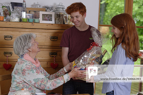 Geburtstagsfeier  Enkelkinder gratulieren der Großmutter mit einem Geschenkkorb  Bayern  Deutschland  Europa