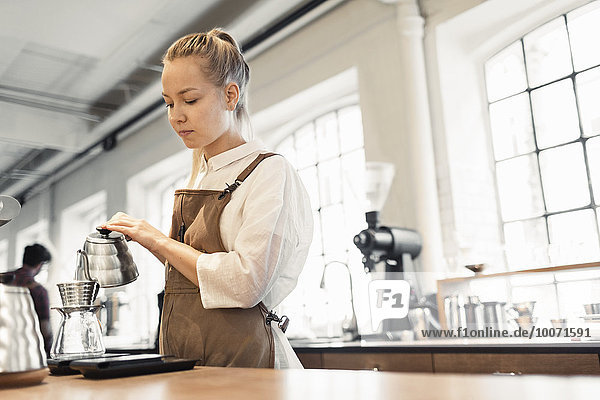 Weibliche Barista gießt kochendes Wasser in den Kaffeefilter im Cafe