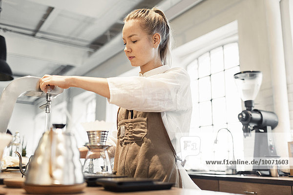 Young female worker preparing coffee at counter