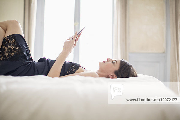 Woman lying on the bed using a mobile phone