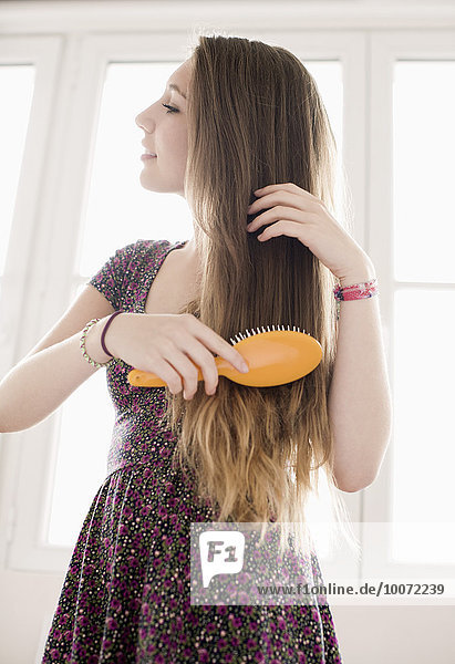 Teenage girl getting hair care with brush