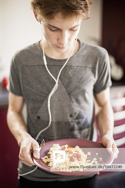 Teenage boy listening to music with breakfast