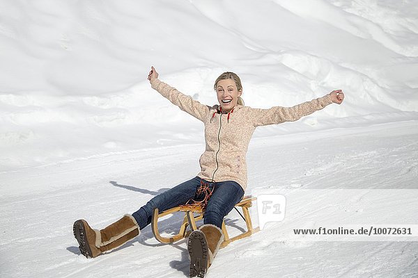 Porträt einer lächelnden Frau auf einem Schlitten im Schnee  Crans-Montana  Schweizer Alpen  Schweiz